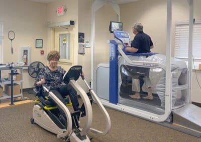 A woman on a workout bike and a man on an anti-gravity treadmill